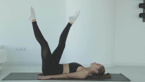 Ayakta yoga yaparken bacaklarını esneten genç bir kadın spor ya da aktif yaşam tarzının bir parçası olarak esneme hareketleri yapıyor. Sporcu kız antrenmandan önce ısınır.. — Stok video