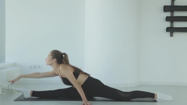 Молодая женщина, которая растягивает ноги в стоящих упражнениях йоги растяжения как часть фитнес-работы или активного образа жизни. Девочка делает разминку перед тренировкой. — стоковое видео