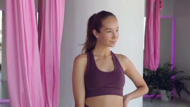 Une jeune fille sportive fait du yoga sur un hamac, des exercices pour la santé. Entraînement dans la salle de gym avec fenêtres panoramiques. — Video