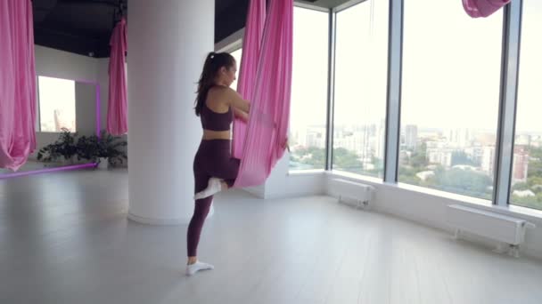 Mladá atletka cvičí jógu na houpací síti, cvičí pro zdraví. Cvičení v tělocvičně s panoramatickým Windows. — Stock video