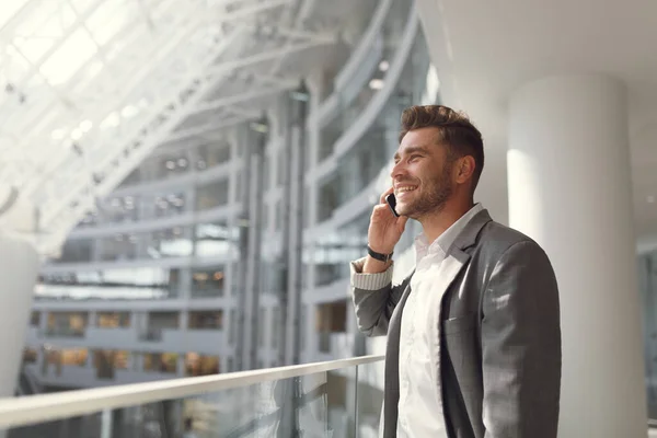 Όμορφος επιχειρηματίας με κουστούμι και μιλάει στο τηλέφωνο στο δρόμο. Πορτρέτο ενός νεαρού άνδρα σε επιχειρηματικό στυλ χαμογελώντας και γελώντας. — Φωτογραφία Αρχείου