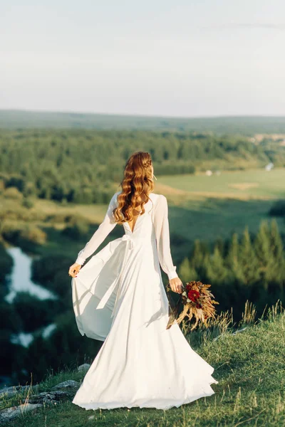 Noiva com um buquê de flores secas andando na natureza. Boho casamento estilo no outono. — Fotografia de Stock