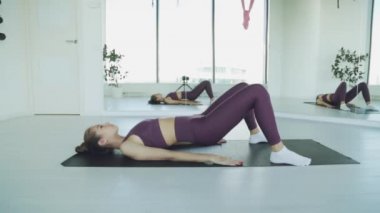 Genç bir atletik kız spor salonunda paspaslarla antrenman yapıyor. Beyaz arka planda kızlar için esneme egzersizleri..