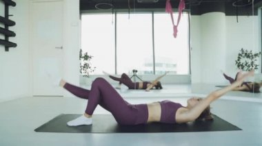 Genç bir atletik kız spor salonunda paspaslarla antrenman yapıyor. Beyaz arka planda kızlar için esneme egzersizleri..