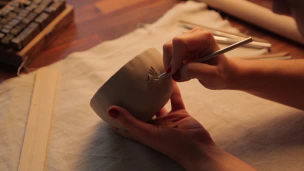 Een kleivaas maken in de werkplaats close-up. De meisjes handen toepassen textuur en serifs op de klei. — Stockvideo
