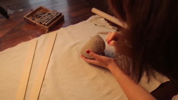 Een kleivaas maken in de werkplaats close-up. De meisjes handen toepassen textuur en serifs op de klei. — Stockvideo