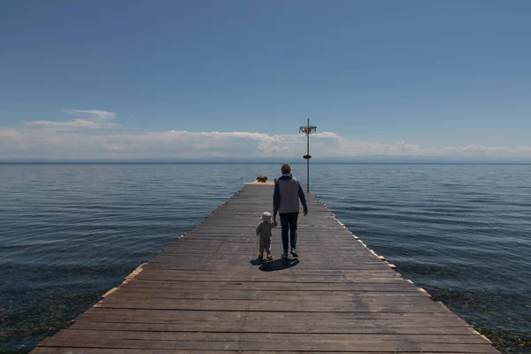 Grandmother and granddaughter walk on the pier on the lake