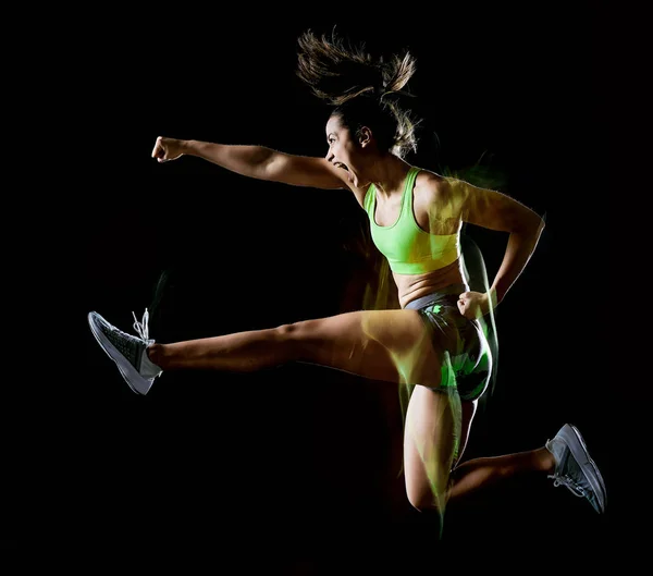 Mulher exercitando exercícios de aptidão isolado fundo preto efeito lightpainting — Fotografia de Stock