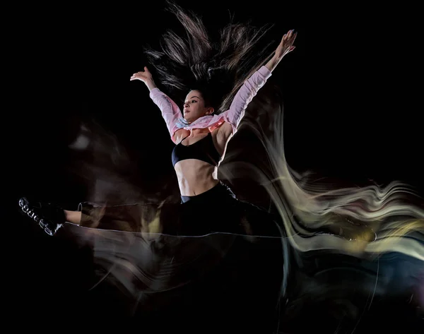 Mujer joven bailarina moderna bailando aislado negro fondo luz pintura — Foto de Stock