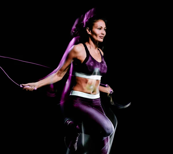 Bela mulher pulando corda fitness exercícios isolado fundo preto — Fotografia de Stock