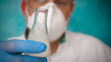 Simyaci bir biyolog, solunum, Gözlük, beyaz bir tıbbi elbisesi, bir şişesi, yeşil bir arka plan, bir bilim tablo içinde bir koruyucu kapak içinde çeşitli maddeler, Dna alır.