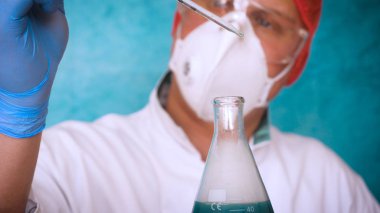 Simyaci bir biyolog, solunum, Gözlük, beyaz bir tıbbi elbisesi, bir şişesi, yeşil bir arka plan, bir bilim tablo içinde bir koruyucu kapak içinde çeşitli maddeler, Dna alır.