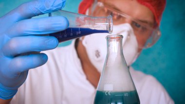 Simyaci bir biyolog, solunum, Gözlük, beyaz bir tıbbi elbisesi, bir şişesi, yeşil bir arka plan, bir bilim tablo içinde bir koruyucu kapak içinde çeşitli maddeler, Dna alır.