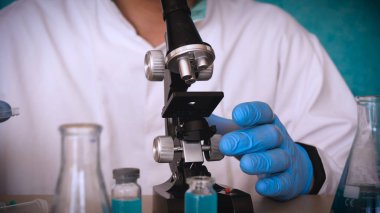 Simyaci bir biyolog, solunum, Gözlük, beyaz bir tıbbi elbisesi, bir şişesi, yeşil bir arka plan, bir bilim tablo içinde bir koruyucu kapak içinde çeşitli maddeler, Dna alır.