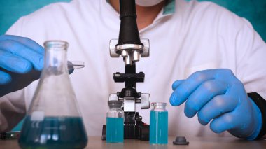 Simyaci bir biyolog, solunum, Gözlük, beyaz bir tıbbi elbisesi, bir şişesi, yeşil bir arka plan, bir bilim tablo içinde bir koruyucu kapak içinde çeşitli maddeler, Dna alır.