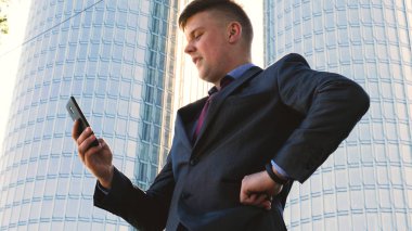 Genç yakışıklı işadamı telefon, kostüm, gökdelen konuşuyor