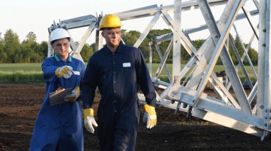 Bir elektrikçi veya Oluşturucusu ve mühendis, sarı ve beyaz kask içinde mavi bir elbise içinde güç için teknik genel bakış kontrol, elektrik direkleri, bir elektrik Kulesi, enerji ve işçi hazırlamak.