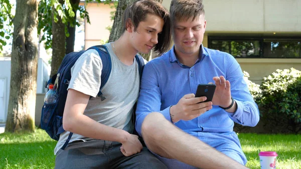Två Vänner Till Student Leende Tittar Telefonen Foton Parken Koncept — Stockfoto