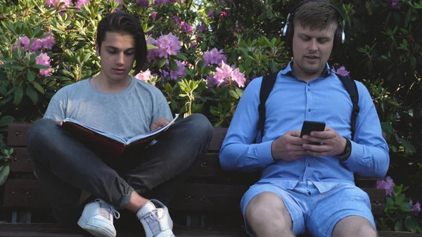 Dos Jóvenes Hermosos Adolescentes Leyendo Libro Escuchando Música Teléfono Móvil —  Fotos de Stock