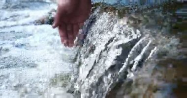 Bir adam elini tutar (ellerini yıkıyor) çeşmede (su), kir onları temizleyerek, ve elinin uzunluğu şelale su tutarak. Konser: su hissedin, yavaş hareket.