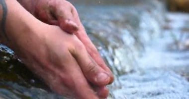 Bir adam elini tutar (ellerini yıkıyor) çeşmede (su), kir onları temizleyerek, ve elinin uzunluğu şelale su tutarak. Konser: su hissedin, yavaş hareket.