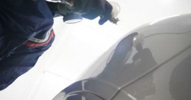 Ağır çekimde, elinde sprey tabanca ve koruyucu gözlüklü bir solunum cihazıyla çalışan bir erkek (erkek), elinde klasörlü bir el feneri ile bir araba motorunu kontrol eder. Otomatik merkez kavramı.