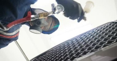 Ağır çekimde, elinde sprey tabanca ve koruyucu gözlüklü bir solunum cihazıyla çalışan bir erkek (erkek), elinde klasörlü bir el feneri ile bir araba motorunu kontrol eder. Otomatik merkez kavramı.