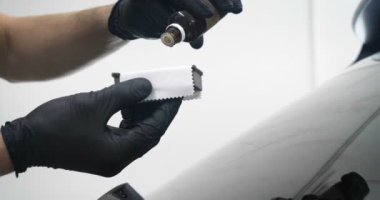 Ağır çekimde, elinde sprey tabanca ve koruyucu gözlüklü bir solunum cihazıyla çalışan bir erkek (erkek), elinde klasörlü bir el feneri ile bir araba motorunu kontrol eder. Otomatik merkez kavramı.