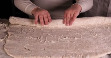 Siyah arka planda küçük bir çocuk, pizzalı çörekler ve çeşitli un ürünleri için hamur hazırlarken babasına (babası) şefe yardım ediyor. 