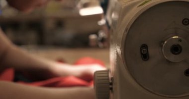 Malzeme her iki tarafını kullanarak kırmızı kumaş üzerinde profesyonel bir makine, nakış (sews) ile terzi dikiş elleri. Konsept: fabrika, ev, Iş başında, profesyoneller.