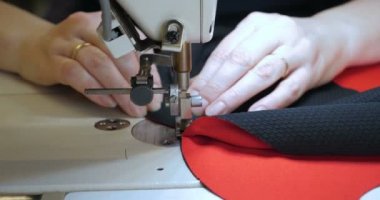 Malzeme her iki tarafını kullanarak kırmızı kumaş üzerinde profesyonel bir makine, nakış (sews) ile terzi dikiş elleri. Konsept: fabrika, ev, Iş başında, profesyoneller.