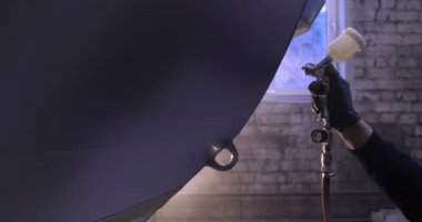 Yavaş hareket profesyonel bir adam (adam) bir garaj (hizmet) bir kazak giymiş çalışma giysileri içinde bir boya tabancası (püskürtme tabancası) ayarlar ve (seramik bir tabaka koyarak) bir yat boyama başlar.