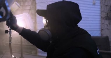 Yavaş hareket profesyonel bir adam (adam) bir garaj (hizmet) bir kazak giymiş çalışma giysileri içinde bir boya tabancası (püskürtme tabancası) ayarlar ve (seramik bir tabaka koyarak) bir yat boyama başlar.