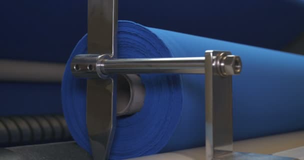 縫製工場はブルーファブリックのロールのサンプルを取ります マシン上のロールチェックの品質をチェックする生地のロールが完全に巻き戻されます コンセプト 品質チェック 新生地 — ストック動画