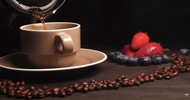 在木桌的背景 咖啡豆的心脏在它可以看到一杯 咖啡酿造 咖啡蒸汽 托盘上的下一个是羊角面包和水果 草莓和蓝莓周围 — 图库视频影像
