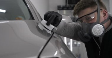 Profesyonel bir erkek (çocuk) arabanın seramik ustası çekmeceye fiber (sünger) bez kullanarak arabanın üzerine seramik koyar, güvenlik gözlükleri ve siyah eldivenler takar ve boya (çizikler) ve boya kompozisyonu (çizikler) için boya yaptıktan sonra arabayı tamamen kontrol eder.