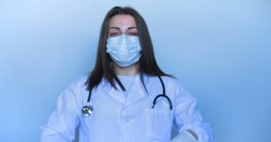 Portre kız (kadın) tıbbi üniforma. Yüzünde bir maske bir koğuşta (hastanede) duruyor, kollarını kesişerek ve gülümsüyor. Konsept: Hemşire, Tıbbi Asistan, İletişim, Selfie, Akıllı Telefon.