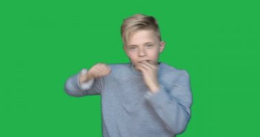 Bir kromakeyin arka planında yavaş çekimde, genç bir erkek (çocuk) farklı duygular gösterir. Yeşil arka plan, Krom Anahtar, Gerçek duygular, Dövüşçü, Moda, Sarışın....