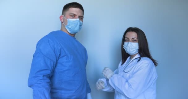 診療所 研究室の2人の若い医師が 同期の手を引っ掻いて 看護師と医師を手に取ります コンセプト 医療用マスク 医療用手袋 — ストック動画
