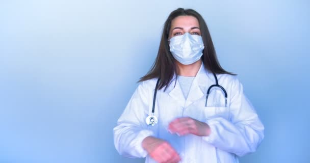 身着医疗服的肖像女孩 她脸上戴着面具 站在病房 交叉着双臂 面带微笑 医疗助理 智能手机 — 图库视频影像