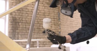 Yavaş hareket profesyonel bir adam (adam) bir garaj (hizmet) bir kazak giymiş çalışma giysileri içinde bir boya tabancası (püskürtme tabancası) ayarlar ve (seramik bir tabaka koyarak) bir yat boyama başlar.