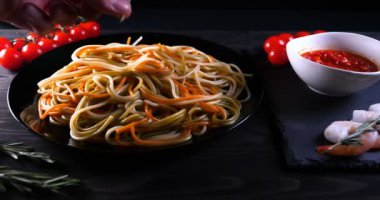 Evde pişirilen yemek (restoranda) aşçı bitmiş makarna tabağını rendelenmiş parmesan peyniri ile mutfak rendesinde süslüyor ve sos ekliyor. Peynir, muhteşem yemek, ağır çekim kavramı.