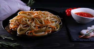 Evde pişirilen yemek (restoranda) aşçı bitmiş makarna tabağını rendelenmiş parmesan peyniri ile mutfak rendesinde süslüyor ve sos ekliyor. Peynir, muhteşem yemek, ağır çekim kavramı.