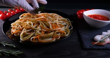 Evde pişirilen yemek (restoranda) aşçı bitmiş makarna tabağını rendelenmiş parmesan peyniri ile mutfak rendesinde süslüyor ve sos ekliyor. Peynir, muhteşem yemek, ağır çekim kavramı.