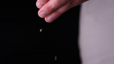 Siyah bir arka plan üzerinde yavaş çekimde, tuz (un) bir yandan strewed olduğunu. Konsept: Zaman, Mutfak, Yaşam, El, Kristal, Kristal Tuz.