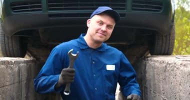 Sokakta neşeli bir araba tamircisi motor ve arabanın alt kısmını tamir, farklı duygular gösterir, büyük bir anahtarı ile dans eder. Kavramı: Hizmet, Joy, Yavaş hareket, Mood, Mutlu, Onarım.