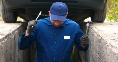 Sokakta neşeli bir araba tamircisi motor ve arabanın alt kısmını tamir, farklı duygular gösterir, büyük bir anahtarı ile dans eder. Kavramı: Hizmet, Joy, Yavaş hareket, Mood, Mutlu, Onarım.