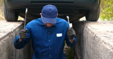 Sokakta neşeli bir araba tamircisi motor ve arabanın alt kısmını tamir, farklı duygular gösterir, büyük bir anahtarı ile dans eder. Kavramı: Hizmet, Joy, Yavaş hareket, Mood, Mutlu, Onarım.