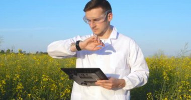 Genç yakışıklı (erkek) biyolog veya agronomist, beyaz bir ceket, gözlük, mavi lastik eldiven, elma ağacı boyunca yürür nem yaprakları, DNA, pipet, analizleri alır. Yakışıklı biyolog veya beyaz tıbbi giysiler, güvenlik gözlükleri içinde agronomist.