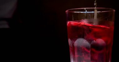 Barmen, bir parti için çeşitli içecekler (kokteyller) hazırlar. Disko veya evde barda meyve soğuk içecekler siyah arka planda görülür.